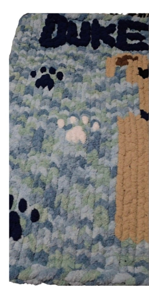 Blanket with 'DUKE' and paw prints on a textured background