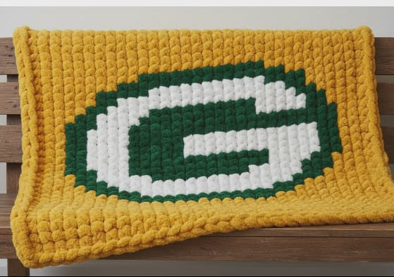 Crocheted blanket with a large letter 'G' on a wooden surface