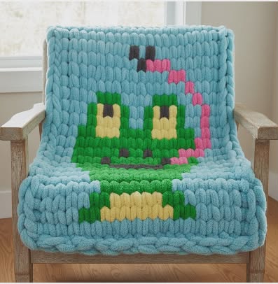 Knitted blanket with a frog character on a wooden chair