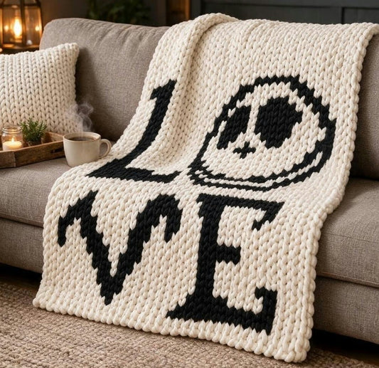 Chunky knit throw blanket draped over a gray sofa in a cozy living room setting, featuring the word LOVE with a skull representing the O.