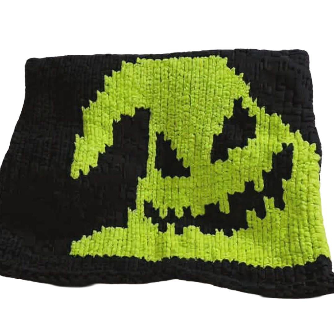 Black and green knitted blanket with a pixelated ghost design on a white background