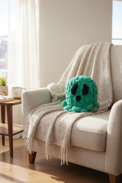 Green crochet ghoston a beige couch with a blanket in a bright room