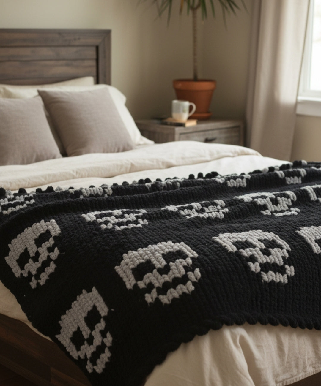 Black and white skull-patterned blanket on a bed in a bedroom setting.