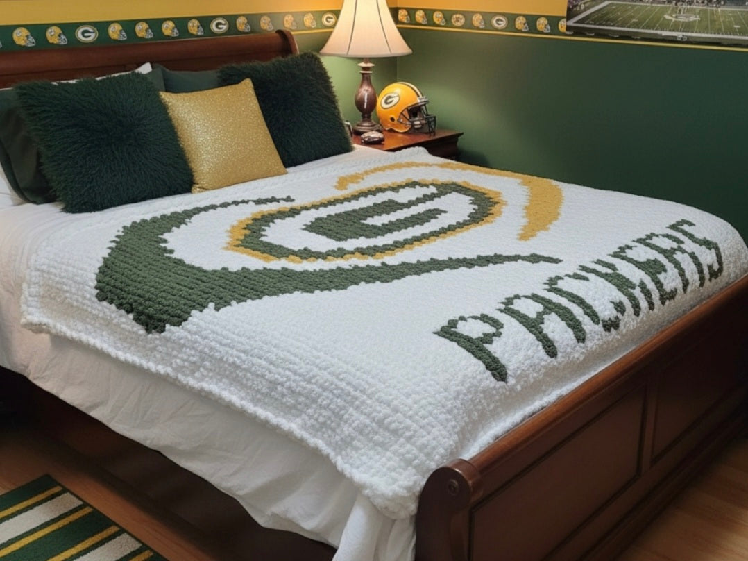 Bedspread with Green Bay Packers logo and text on a bed in a room.