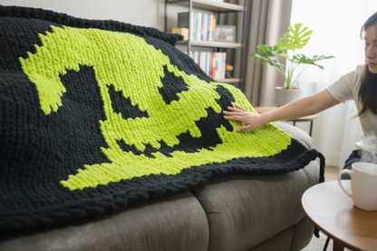Person holding a green and black patterned blanket on a couch in a living room.