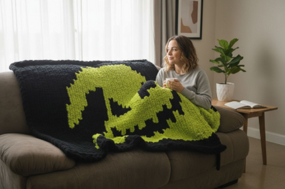 Woman sitting on a couch with a colorful blanket, holding a mug in a cozy living room.