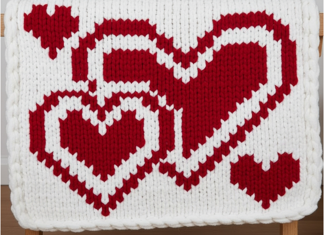 Knitted blanket with red heart pattern on a white background
