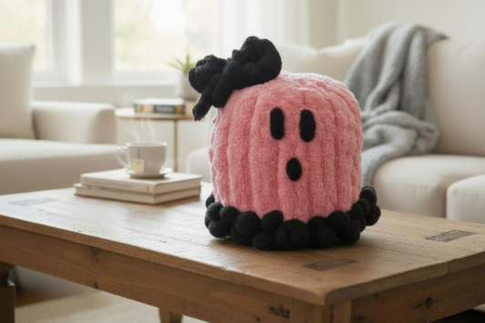 Pink and black plush ghost on a wooden coffee table in a living room setting