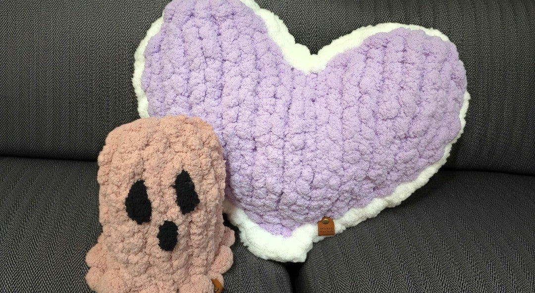 Heart-shaped pillow and ghost plush toy on a dark surface