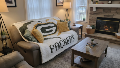 Living room with a couch covered by a Packers blanket, coffee table, and fireplace.